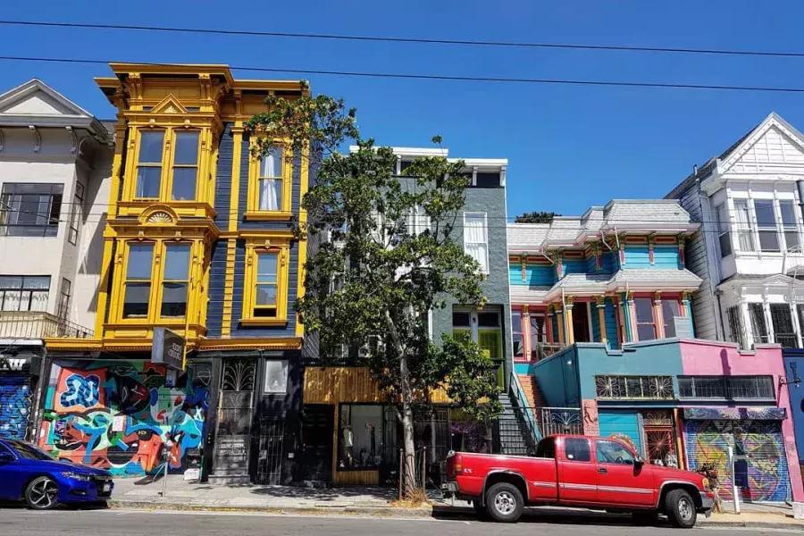 Blick auf farbenfrohe Gebäude in der Haight Street mit entlang der Straße geparkten Autos. San Francisco, Kalifornien.