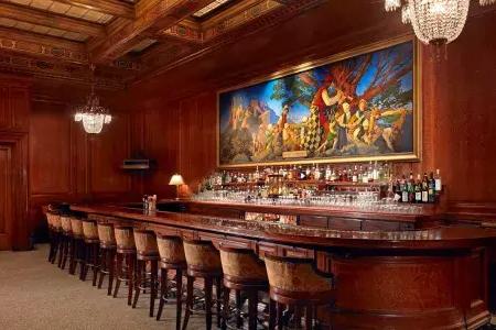 The bar at the Palace Hotel, which features wood-paneled walls and a painting titled The Pied Piper of Hamelin.
