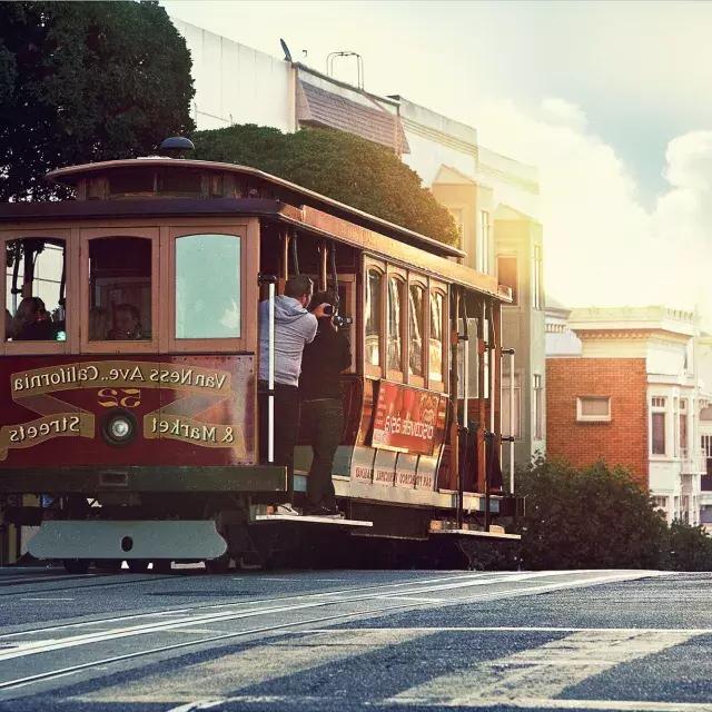 Um teleférico contorna uma colina em São Francisco com passageiros olhando pela janela.